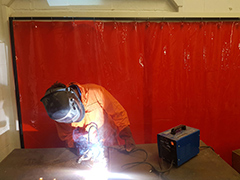Welder in front of a welding screen